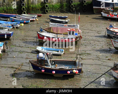 Fishing boats lie on the mud at low tide in the inner harbour at Mevagissey in Cornwall. Stock Photo