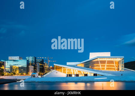 Oslo, Norway. Night Evening View Of Illuminated Norwegian National Opera And Ballet House Among Contemporary High-Rise Buildings. Blue Sky Background, Stock Photo