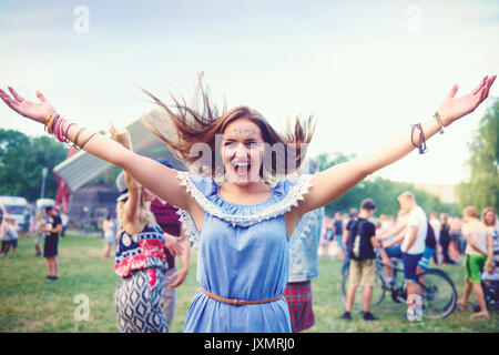 Young boho woman dancing and jumping for joy at festival Stock Photo