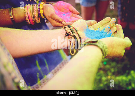 Pink and blue chalk cupped in young couples hands at festival Stock Photo
