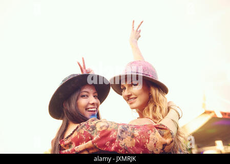 Portrait of two young female friends making peace sign at festival Stock Photo