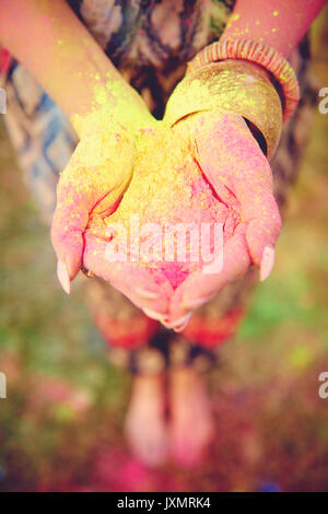 Waist down view of young boho woman with coloured chalk powder in cupped hands at festival Stock Photo