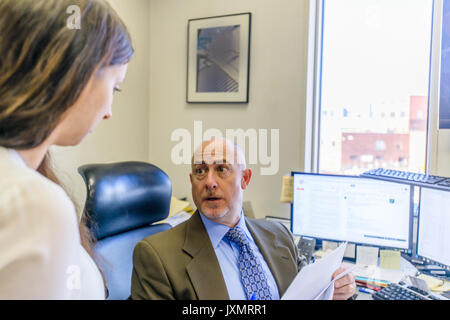 Over shoulder view of manager having discussion with office worker at office desk Stock Photo