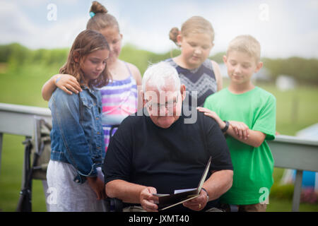 Grandfather surrounded by grandchildren giving him greeting card Stock Photo