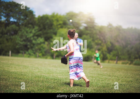 Girl playing baseball on field Stock Photo