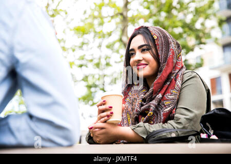 Woman wearing hijab enjoying coffee with friend Stock Photo