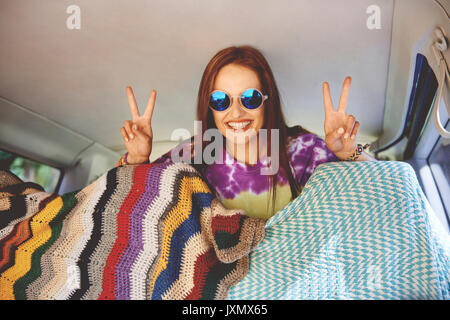 Portrait of young boho woman making peace sign in recreational van Stock Photo