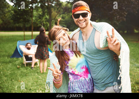 Portrait of young boho couple making peace signs at festival Stock Photo