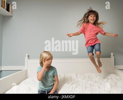 Girl in mid air jumping on bed Stock Photo