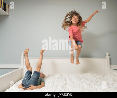Girl in mid air jumping on bed Stock Photo
