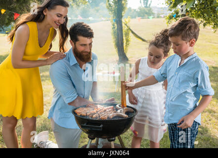 Father and son preparing meat on charcoal barbecue grill during  Stock Photo