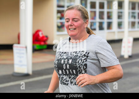 Middle aged overweight woman running as part of plan to lose weight and get fit, at the Worthing Vitality Parkrun event. Stock Photo