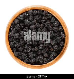 Aronia berries in wooden bowl. Dried ripe black chokeberries, Aronia melanocarpa. The Fruits are used as flavoring or colorant. Macro food photo. Stock Photo