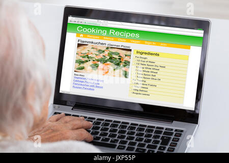 Close-up Of Senior Woman Using Laptop For Learning Recipe On Website At Home Stock Photo