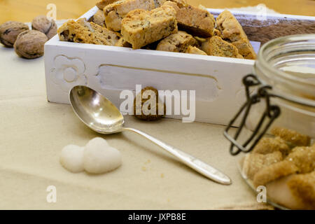 Italian tozzetti in a white wooden box with heart shaped sugar cubes and a silver spoon. Side view. Landscape format. Stock Photo