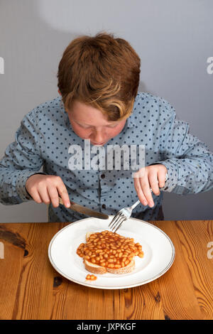 11-year old boy eating beans on toast for breakfast Stock Photo