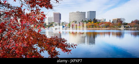 Oakland, California, Lake Merritt view of skyline across water. Colorful tree with red fall leaves in foreground. Stock Photo