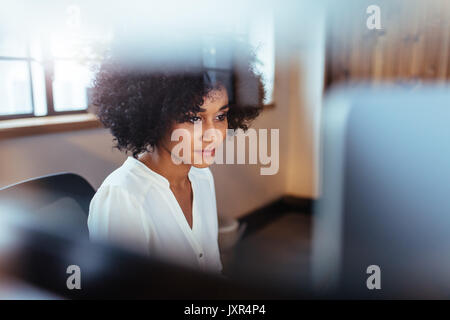Shot of young african woman working in her office. Beautiful female executive sitting at her desk looking at computer. Stock Photo
