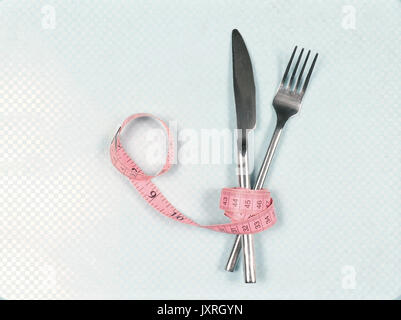 Knife and fork wrapped inside pink tape measure Stock Photo