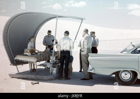 Vintage photo of an American family having a picnic and Barbecue at White Sands National Monument, New Mexico,  in 1956. Shows an awning and car of the period, together with fashion of the period. Stock Photo