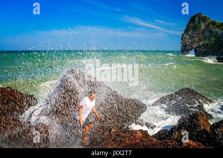 Man escaping incoming big wave on the coast in Thailand Stock Photo