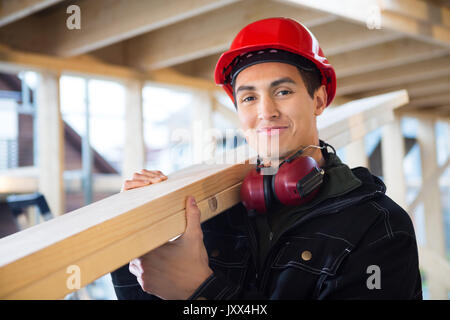 Carpenter Carrying Wood On Shoulder At Construction Site Stock Photo