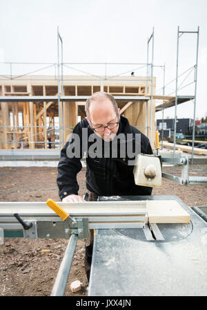 Carpenter Using Table Saw To Cut Wood At Site Stock Photo