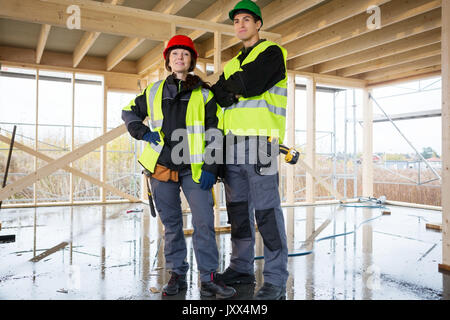 Confident Female Carpenter Standing By Colleague At Construction Stock Photo