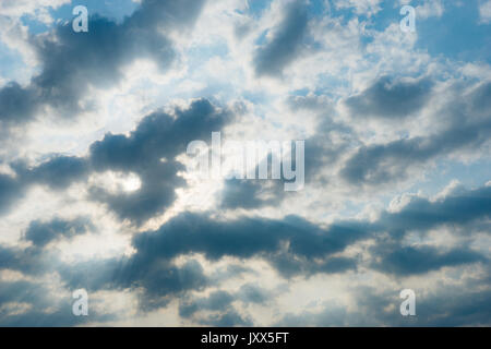 Sun shining through the clouds on blue sky, nature background Stock Photo