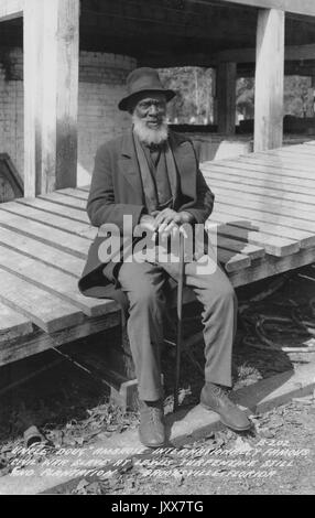 Ambrose Hillard Douglas, an African American Civil War slave, sits outside holding a cane on the Lewis plantation and turpentine still, 1940. Stock Photo