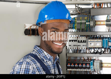 Male Technician Holding Clipboard While Examining Fusebox Stock Photo
