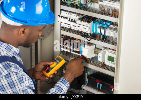 Close-up Of Male Electrician Checking Fuse Box With Multimeter Stock Photo