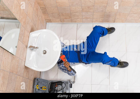 High Angle View Of Male Plumber Repairing Sink In Bathroom Stock Photo