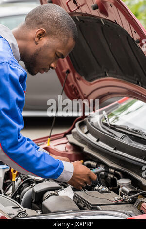 Close-up Of Male Mechanic Checking Car Battery Level With Multimeter Stock Photo