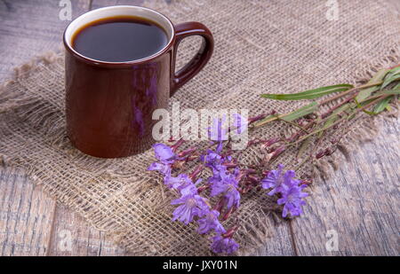 Medicinal plant chicory: flowers. The roots of the plants are used as a substitute for coffee. Drink from chicory in a cup on the old wooden table. Rustic style, selective focus Stock Photo