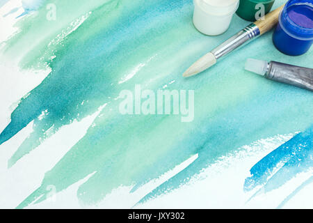 abstract hand painted watercolor background on textured paper in green color with paints and brush Stock Photo