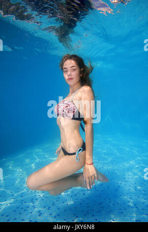 Beautiful young woman in bikini posing under water in pool Stock Photo