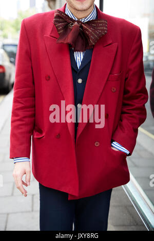 Man in red jacket over blue suit and bow scarf, vertical Stock Photo