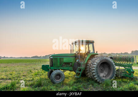 Tractor in a field on a rural Maryland farm at sunset with sun rays Stock Photo