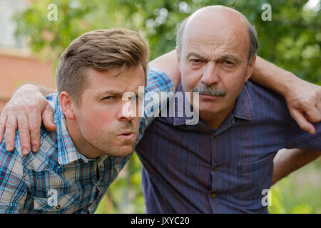 Portrait of doubting men. Dad and son look forward and frown Stock Photo