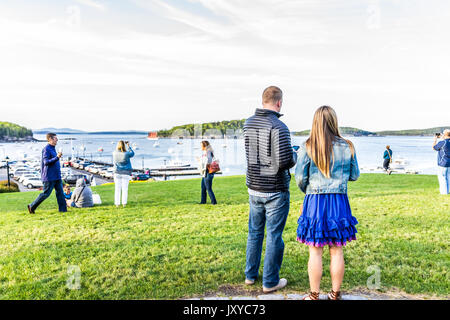 Bar Harbor, USA - June 8, 2017: Young couple walking on green grass hill in park downtown village in summer by boats Stock Photo