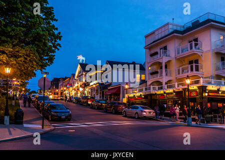 Bar Harbor, USA - June 8, 2017: People walking sidewalk street by Main road in downtown village during evening night Stock Photo