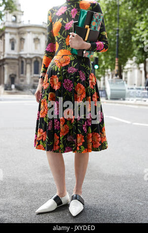 Woman in floral dress and white shoes, low section Stock Photo