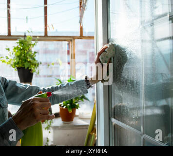 Caucasian woman cleaning window with rag and spray bottle Stock Photo