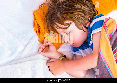 Caucasian boy laying on towels sleeping Stock Photo