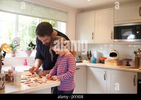 Father And Daughter Baking Halloween Cookies Together Stock Photo