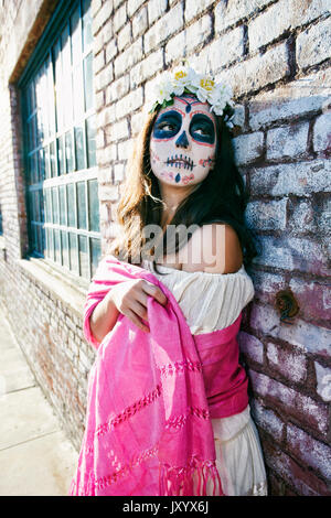 Mixed Race woman on sidewalk wearing skull face paint Stock Photo