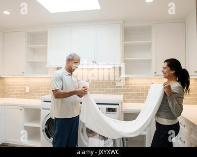 Couple folding towel in modern laundry room Stock Photo