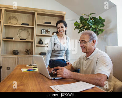 Older couple using laptop in home office Stock Photo