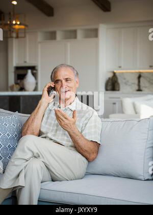 Caucasian man sitting on sofa talking on cell phone Stock Photo